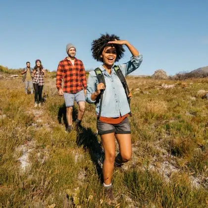 Group of young friends hiking in countryside. Multiracial young people on country walk.